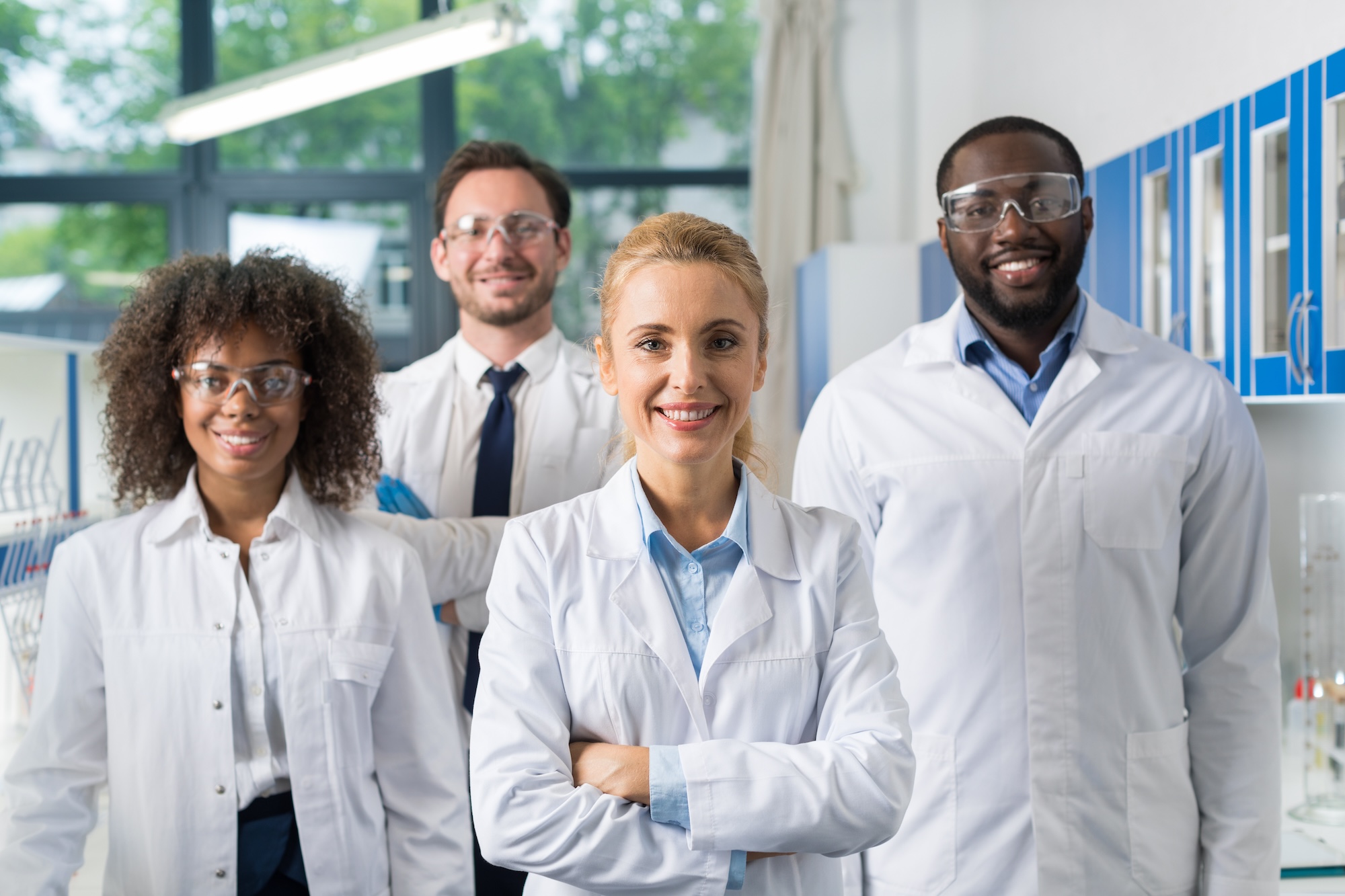 Four diverse medical professionals in white smile for the camera